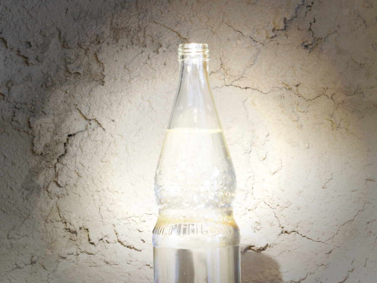 Titelbild zum Artikel über Wasser für die Kaffeezubereitung. Zu sehen ist eine hell erleuchtete Glaswasserflasche.